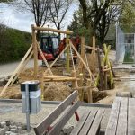 Spielplatzbau mit Holzgerüsten und Bagger im Einsatz