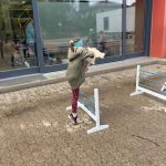 Mädchen springt im Freien über Hürdenlauf hindurch