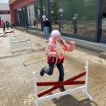 Mädchen überspringt Hürde auf einem Schulhof