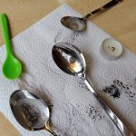 Löffel mit Ruß auf Küchentuch neben Kerzen