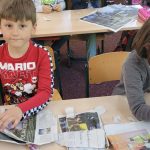 Kinder basteln im Klassenzimmer mit alten Zeitungen.