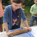 Mädchen bearbeitet Stoff mit Nudelholz im Freien