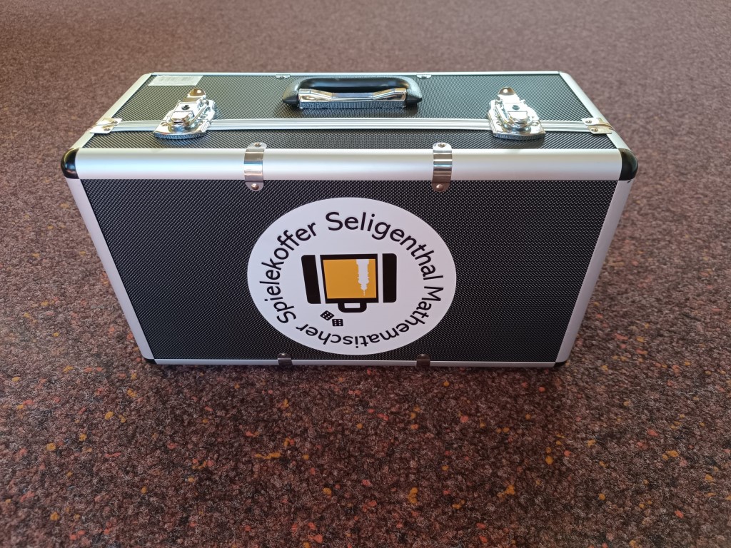 Silberner Spielekoffer Seligenthal auf Teppichboden