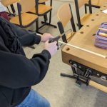 Person sägt Holz an einem Tisch im Klassenzimmer