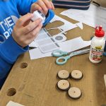 Kind bei Bastelarbeit mit Holz und Papier