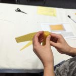 Person wickelt Bienenwachs um eine Kerze