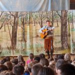 Mann spielt Gitarre auf Kinderveranstaltung vor Publikum