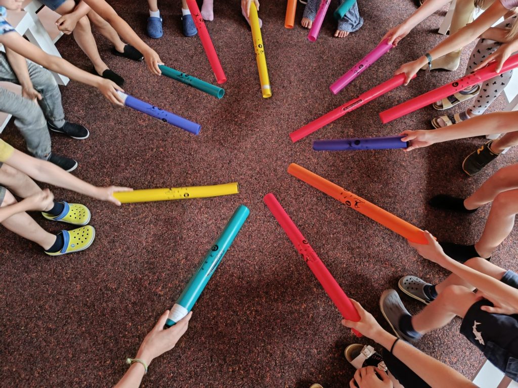 Kinder spielen mit bunten Musikinstrumenten auf Teppich.