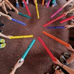 Kinder spielen mit bunten Musikinstrumenten auf Teppich.