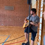 Mann spielt Gitarre in Turnhalle auf Lautsprecher