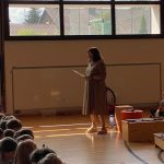 Lehrerin spricht vor Kindern in der Turnhalle