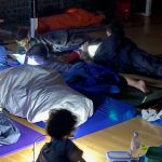 Kinder lesen nachts mit Taschenlampen in Schlafsäcken