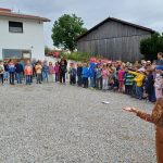 Kindergruppe steht im Freien in einem Kreis.