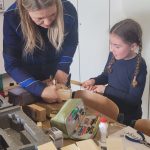 Zwei Frauen arbeiten gemeinsam an Holzprojekt.