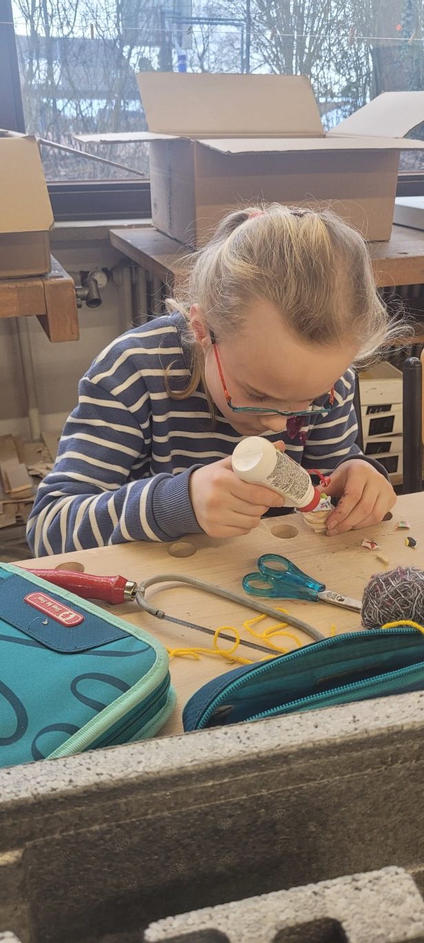 Kind bastelnd mit Kleber im Kunstunterricht genießen