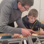 Erwachsener zeigt Kind Werkzeuge im Unterricht